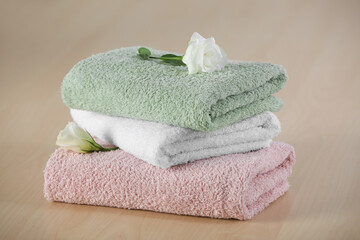 Soft folded towels with eustoma flowers on wooden table