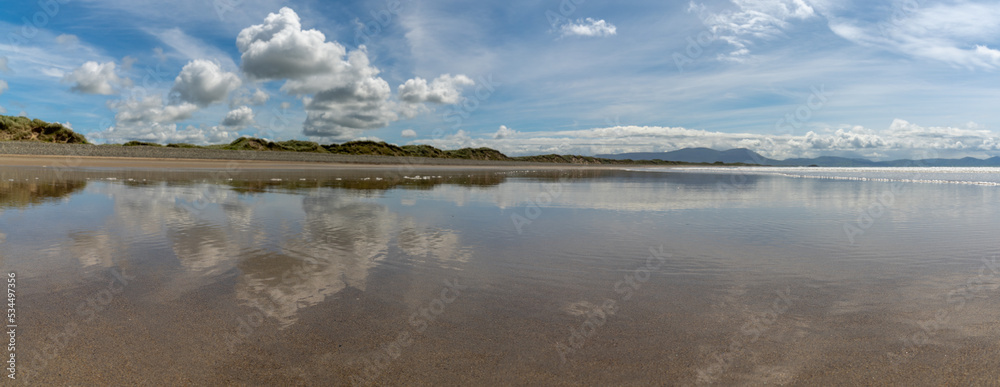 Poster panorama landscape of an empty golden sand beach with reflections of sky and sand dunes