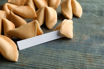 Tasty fortune cookies and paper with prediction on blue wooden table, closeup. Space for text