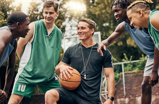 Basketball coach talking to his team during a training session on outdoor court. Teamwork, motivation and inspiration speech from trainer for basketball team having fun and learning in a sports game