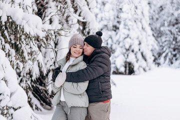 Fototapeta na wymiar Young couple in love hugging in the winter forest and having fun spending time together.Winter,Valentine's day,newlyweds, tenderness and love.
