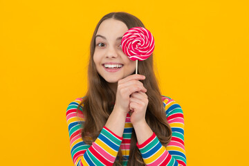 Teenager girl eating sugar lollypop. Candy and sweets for kids. Child eat lollipop popsicle over yellow isolated background. Yummy caramel, candy shop.