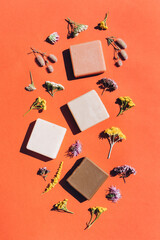 Handmade organic soap bars made with natural ingredients, flowers and herbs over orange background....