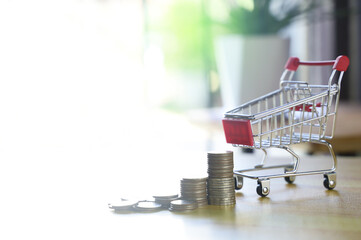 Mini shopping cart and coin on wooden table.Online shopping concept.
