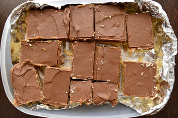 Millionaire's shortbread or chocolate slices or chocolate caramel in a plastic box.  Flat lay top view photo.  