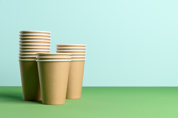 Stack of disposable eco friendly coffee cup on the pastel blue background. Biodegradable concept. Copy space.