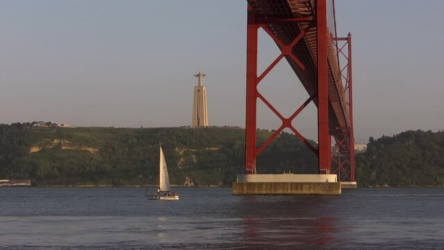 25 Abril bridge over boats in Tejo River and Sanctuary of Christ the King on horizon, Portugal