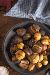 Roasted chestnuts in cast iron pan on an old board