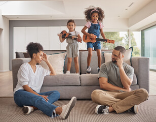 Stress, family and energy with kids playing music on a guitar in the living room at home while...