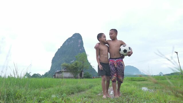 Two children enjoying with football in green mountain background in a countryside Laos.
