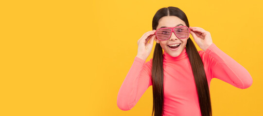 surprised kid in glamour party eyeglasses on yellow background, fun. Child face, horizontal poster, teenager girl isolated portrait, banner with copy space.