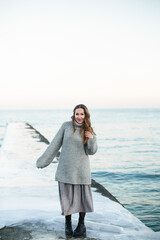Young happy woman wearing a wool sweater running on the beach in winter enjoying the snowfall