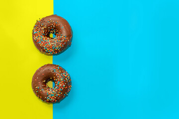 Donuts with chocolate glaze and colored sprinkles of round shape on a colored background