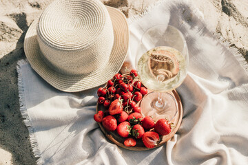 Straw beach hat with brim for sun protection with a plate of fruit and wine.