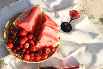 Champagne with a tray of fruits, strawberries and cherries on a picnic.