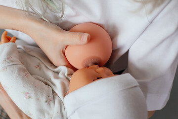 Photo of hands holding model of female breast and baby doll closeup. Training for pregnant women with qualified lecturer. Online study, lactation, nutrition, breast feeding, newborns care - obrazy, fototapety, plakaty