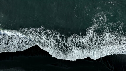 Beautiful aerial view of black beach. Sea ocean waves reaching shore. - Powered by Adobe