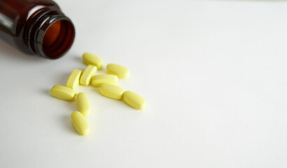 Vitamins for women. Yellow capsules on a white background with a brown bubble.