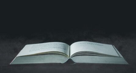 Open book on wooden table, with smoke floating up on dark abstract, idea management, innovation, knowledge technology, inspiration concept, search for new ideas and problem-solving solutions