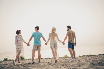 Photo of bonding best friends hold hands walk coast look sunset wear boho outfit nature seaside beach outdoors