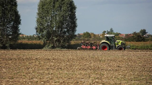tractor with harrow system plowing ground on cultivated farm field