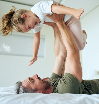 Family, dad and lifting daughter on bed while having fun and enjoying time together bonding during airplane game family activity. Playing, support and laughing man and girl child in bedroom at home