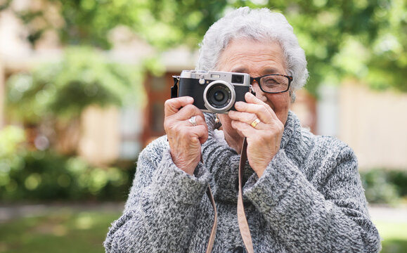 Retirement, relax and elderly woman with photographer hobby to enjoy pension leisure in garden. Satisfied, focused and senior lady with camera busy with nature photography outside nursing home.