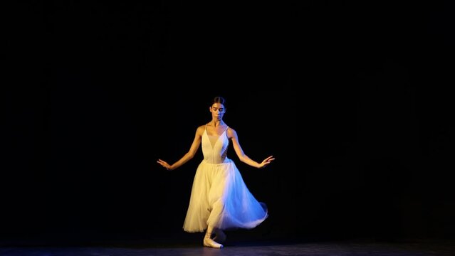 Graceful ballerina in elegant white dress practicing base movements in ballet dance. Concept of beauty, tenderness, achievement, skills