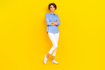 Fototapeta na wymiar Full length photo of adorable good mood girl dressed blue shirt arms folded smiling isolated yellow color background