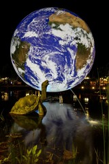 Sculpture fountain of a giant turtle with a large hologram of the planet earth in the background