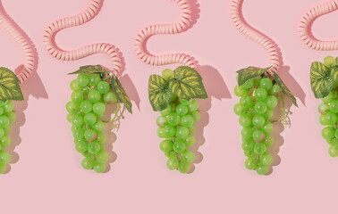 Autumn creative layout made with bunches of green grapes and spiral phone handset cords on pastel baby pink background. Vintage retro aesthetic 80s or 90s fashion concept. Minimal autumn season idea.