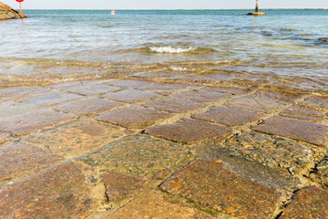 Pavés carrés et colorés d'une route submergée entre une île et le continent. Passage du Gois, Noirmoutier