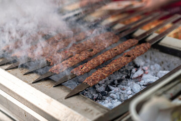 Traditional Adana kebabs are grilling on a barbecue, close up, smoke
