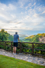 Asian male tourists looking at the mountain view and fog in the morning at canyon Nam Nao in Phetchabun Province, unseen Thailand.