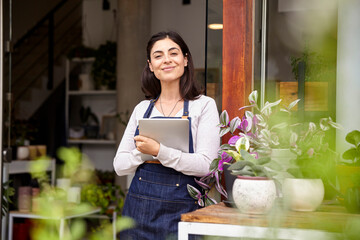 Smiling garden center worker holding digital tablet
