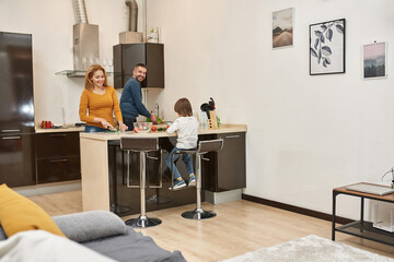 Little boy use tablet while parents cook salad