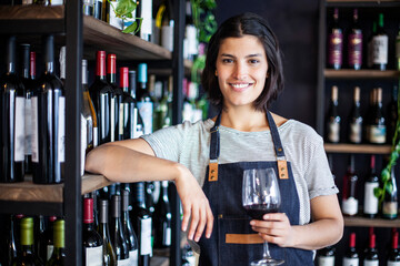 Female sommelier holding glass of wine while looking at the camera