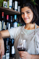 Female sommelier holding glass of wine while standing in liquor store