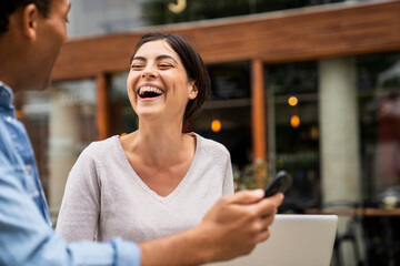 Side shot of diverse couple having a good time and laughing with their online content