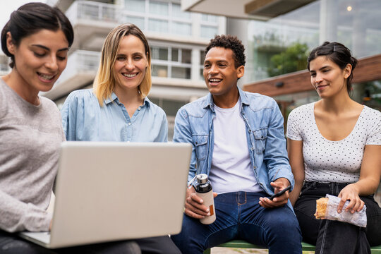 Diverse group of co-workers discussing work matters while working outdoors