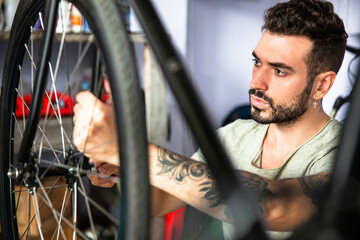 Fototapeta na wymiar Young adult male mechanic repairing bicycle in workshop