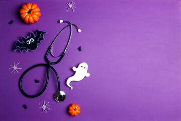 Stethoscope and Halloween decorations on purple background with copy space.