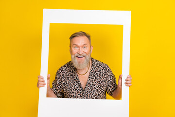 Photo portrait of handsome granddad hold photo frame window smiling wear trendy leopard print clothes isolated on yellow color background