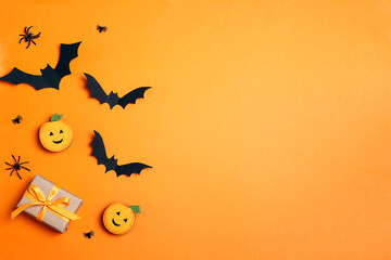 Fototapeta na wymiar Gift box with funny pumpkins, spiders and bats on orange background.