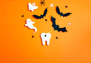 White funny creepy tooth with Halloween decorations on orange background.