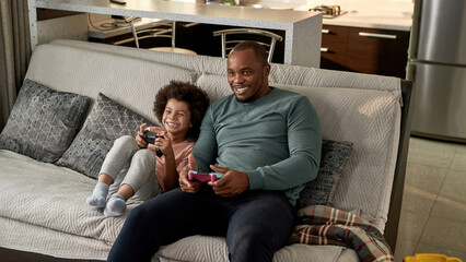 Joyful son and smiling father playing video game