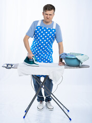 a man in a blue apron, rubber gloves, a blue t-shirt, jeans and white sneakers with an ironing...