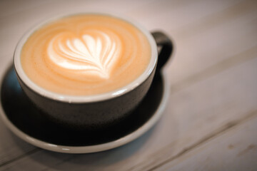 Cup of coffee soya latte art and coffee beans on old wooden background