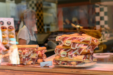 Store window with trays of serrano ham bread sandwiches.