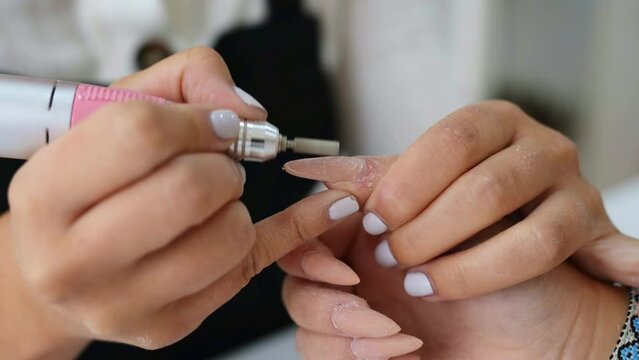 Crop nail artist removing nail polish of customer in salon